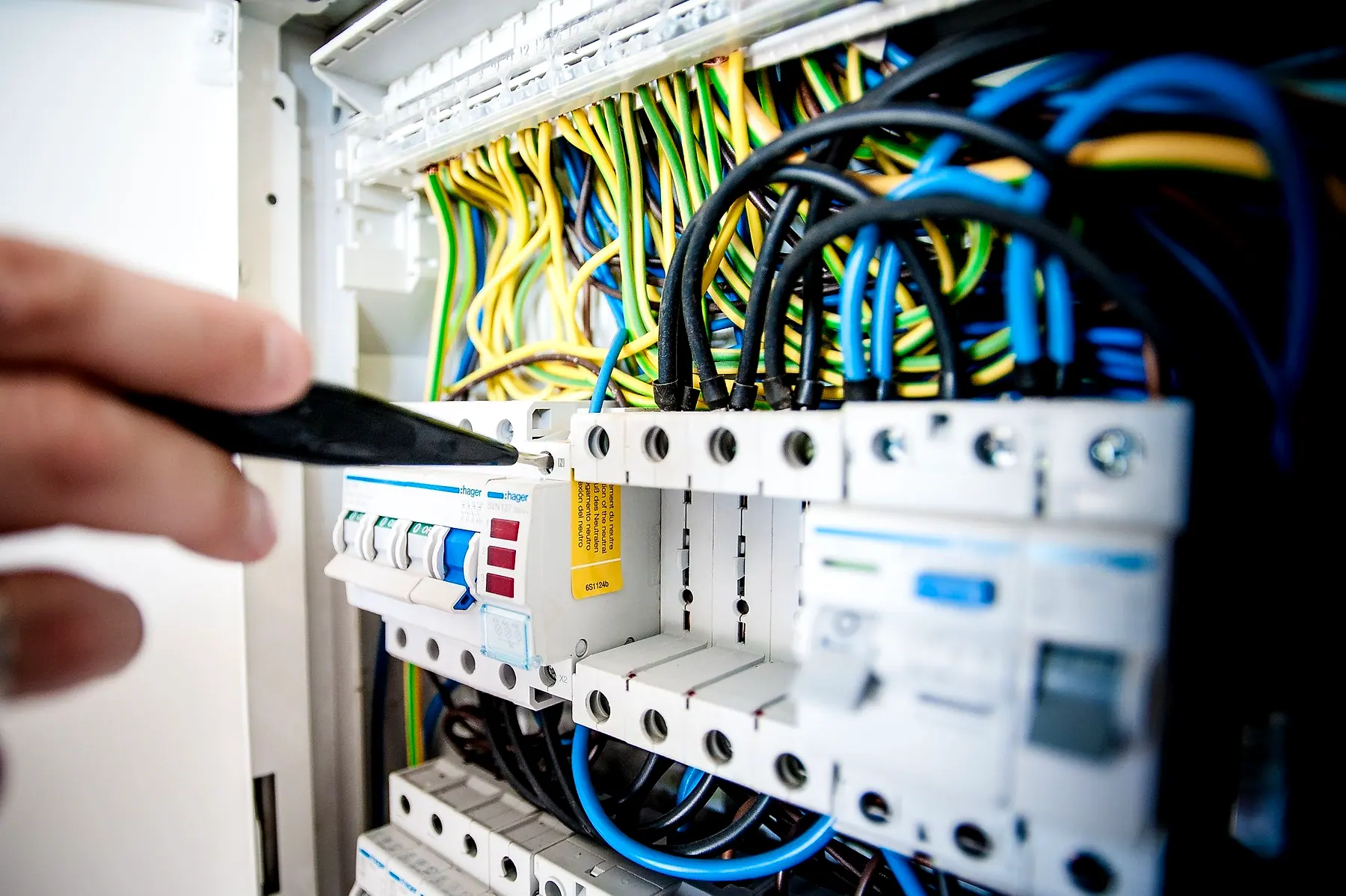 An electrician's hands working on the wiring of a distribution board