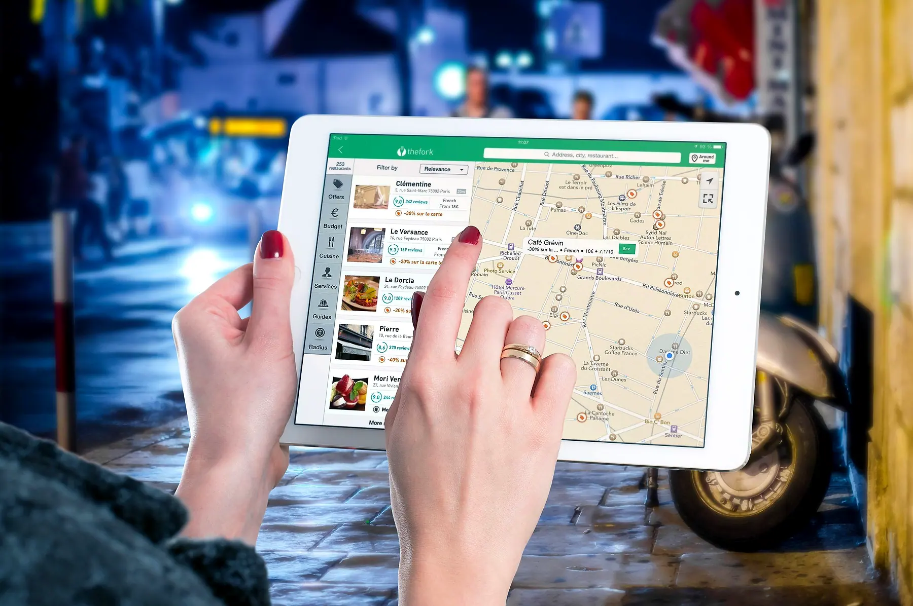 A hand tapping a tablet showing a map of nearby places beside a list of listings with review scores