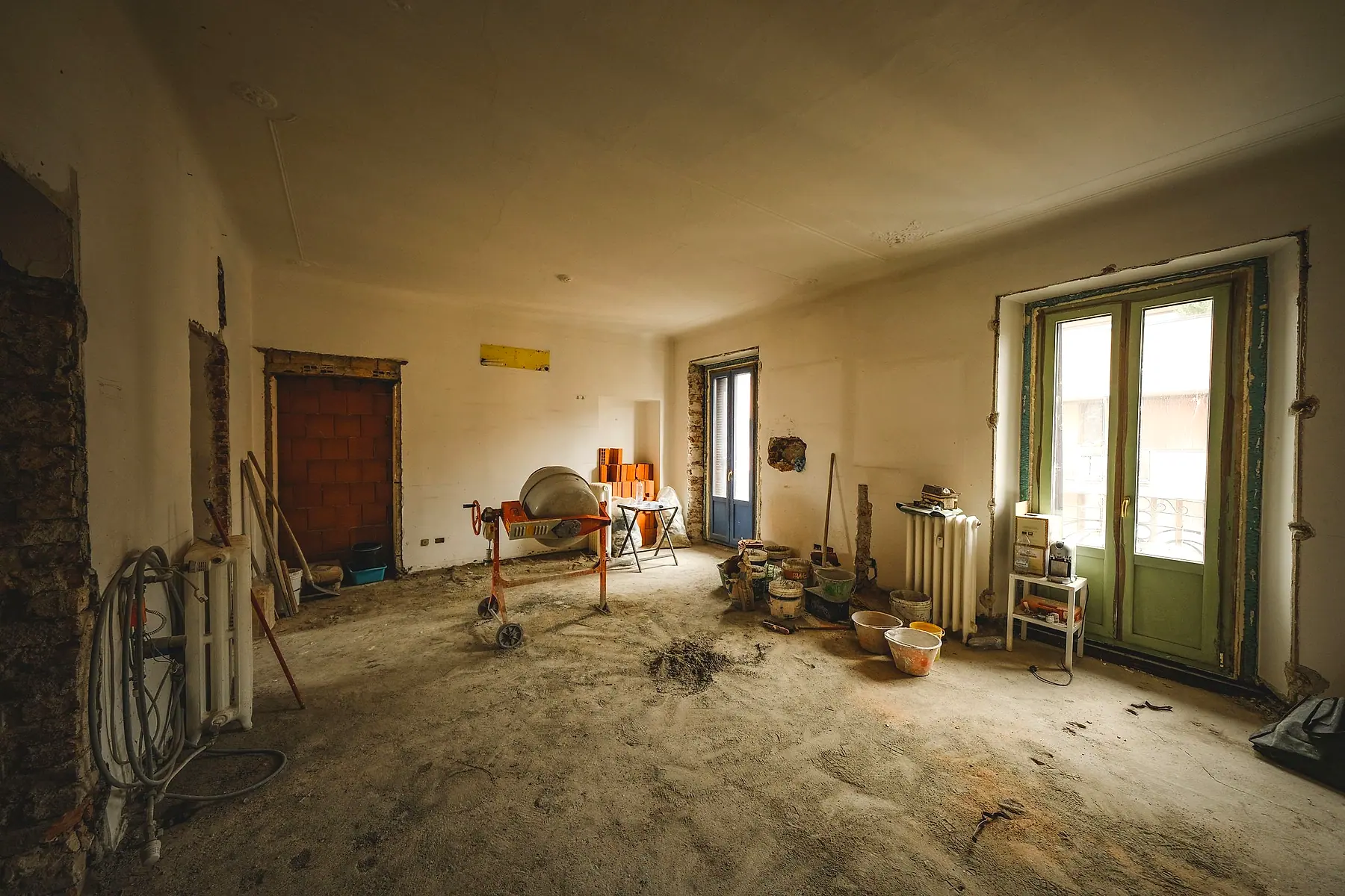 A room mid-renovation, with bare plaster, tools and building materials across the floor